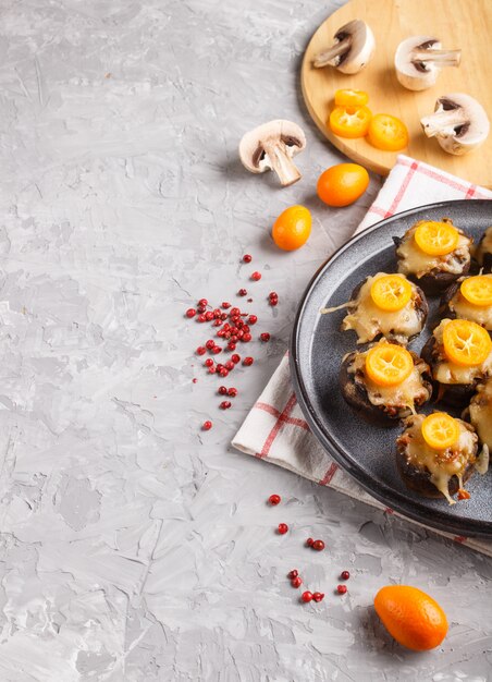 Stuffed fried champignons with cheese, kumquats and green peas on gray 