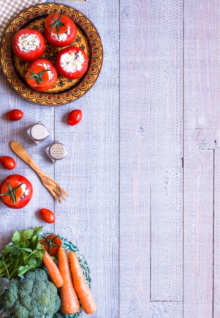 Stuffed tomatoes with cheese, and different vegetables, on a wooden background,