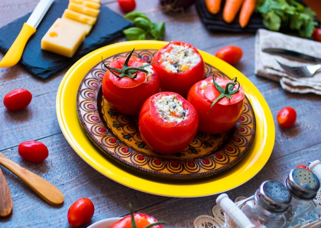 Stuffed tomatoes with cheese, and different vegetables, on wooden table