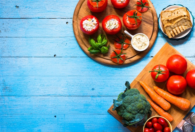 Stuffed tomatoes with cheese, and different vegetables on a wooden table