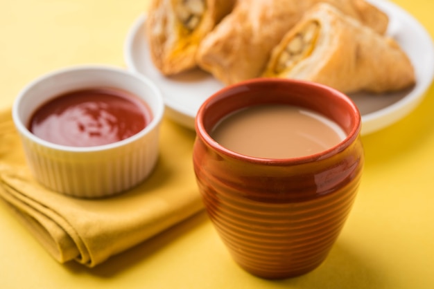 Stuffed vegetable puff or samosa, famous Indian Bakery snack, served with Tomato Ketchup and hot tea, selective focus