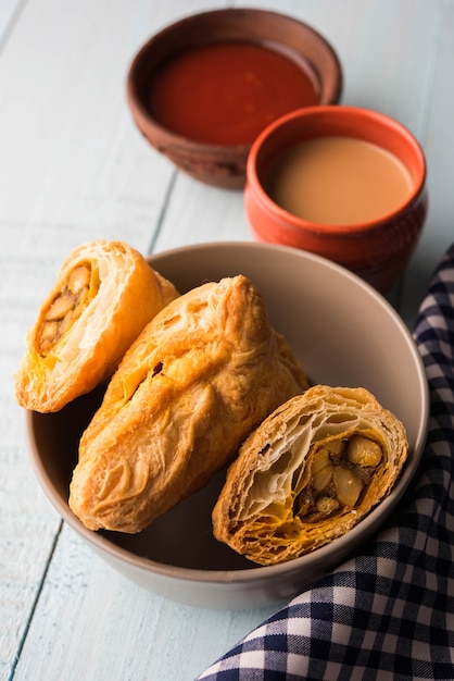 Stuffed vegetable puff or samosa, famous Indian Bakery snack, served with Tomato Ketchup and hot tea, selective focus