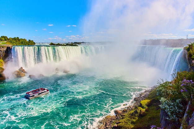 Stunning Niagara Falls view of Horseshoe Falls with ship for tourists approaching mist