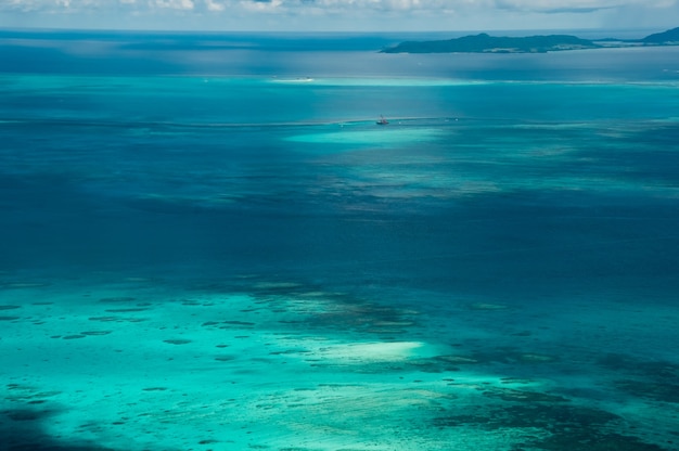 Stunning view of airplane, coral reefs, blue and light green sea, island on background.