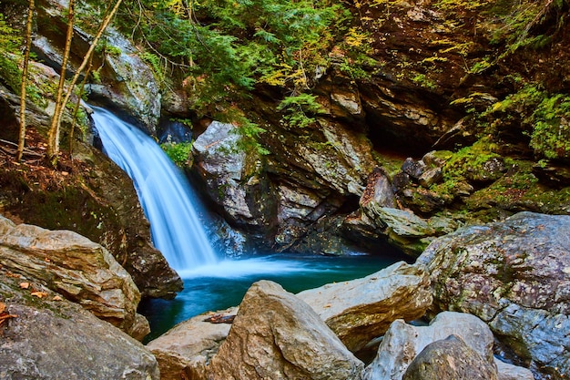 Stunning waterfall into boulders surrounded by forest and cliffs