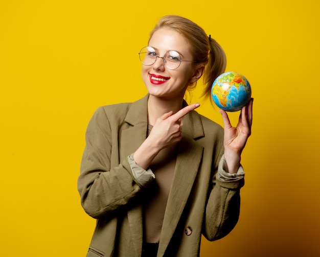 Style blonde woman in jacket hold Globe on yellow