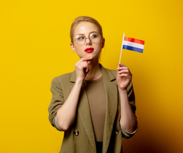 Style blonde woman in jacket with Dutch flag on yellow