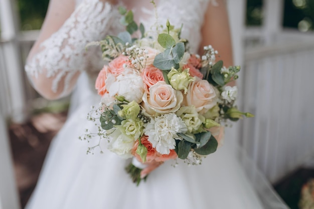 Style floral arranging wedding concept young woman dressed in extremely beautiful snowy white dress with puffy skirt is holding great bunch of different flowers stretched with yellow ribbons