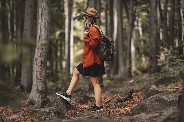 Style girl in hat with backpack in a summer time Mixed coniferous forest