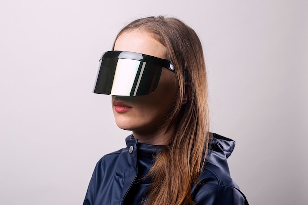 Style woman in virtual reality glasses and in a blue jacket on a light background.