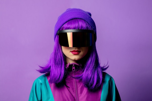 Style woman in VR glasses and 80s tracksuit on violet wall