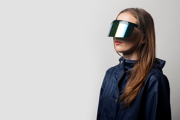 Style woman in VR glasses and in a blue jacket on a light background