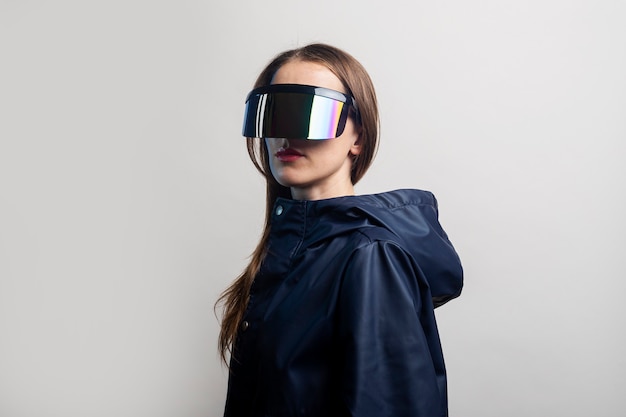 Style woman in VR glasses and in a blue jacket on a light background.