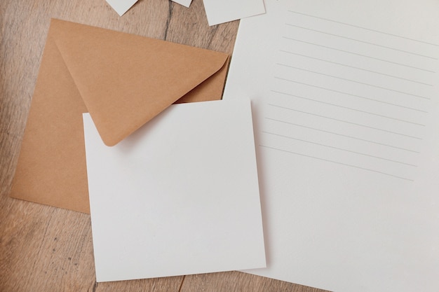 Styled craft envelope, blank card on wooden background. Flat lay. Mockup template. View from above. Top view