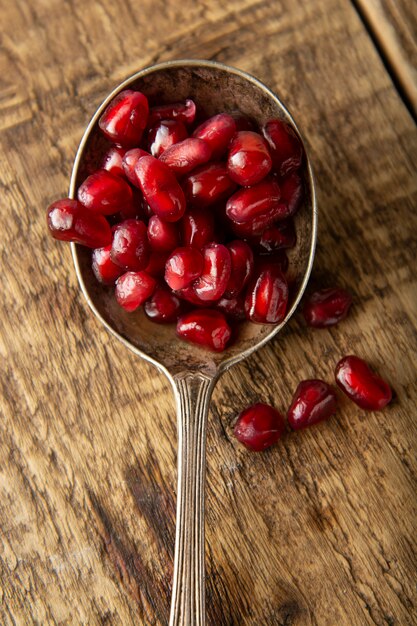 Styled Pomegranate seeds, rustic wooden background. Detox, diet, fruits.