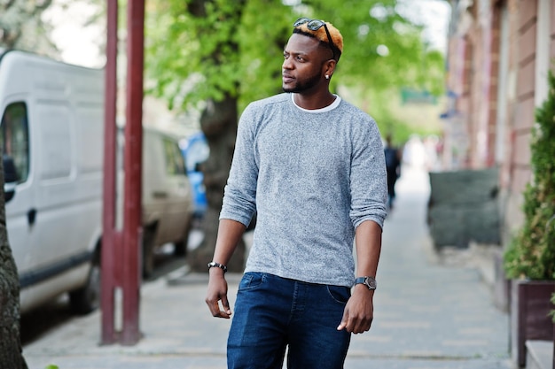 Stylish african american boy on gray sweater and black sunglasses posed on street Fashionable black guy