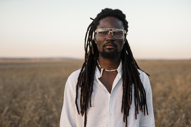 stylish african man in glasses in the field in summer