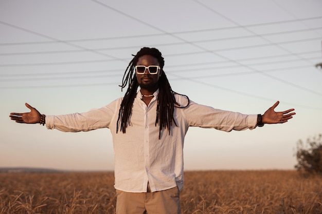 stylish african man in sunglasses in the field in summer