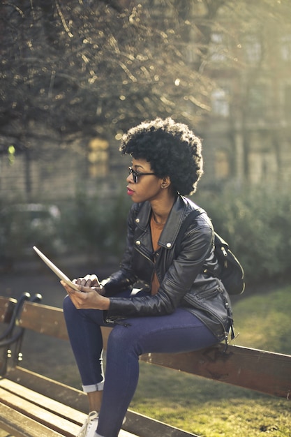 Stylish Afro woman in a park with a tablet