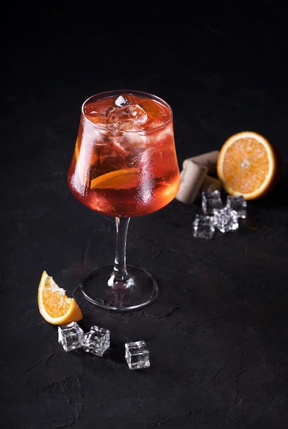 Stylish alcoholic aperol spritz trendy cocktail with orange slice on black background Classic italian aperol