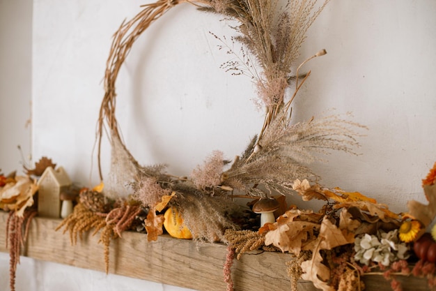 Photo stylish autumn decor of fireplace mantel in living room pumpkins autumn leaves wreath pine cones candle on rustic wood on fireplace fall season decoration thanksgiving and halloween