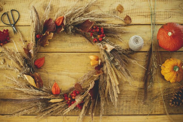 Photo stylish autumn wreath on rustic table flat laywreath with grass berries pumpkin scissors on wood