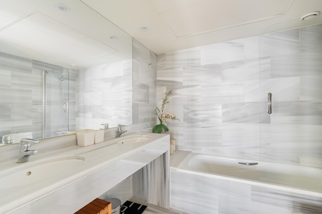 Stylish bathroom with a mirror sink and cabinets on the backdrop of a bathtub in a new apartment the