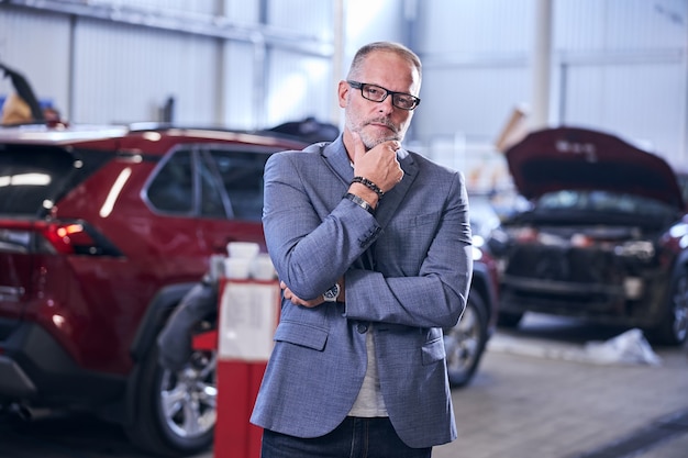 Stylish bearded man standing at car repair service station