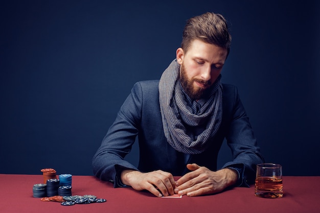 Stylish bearded Man in suit and scarf playing in dark casino