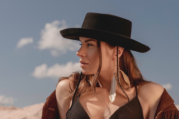 Stylish beautiful cowgirl posing in desert Girl in cowboy hat