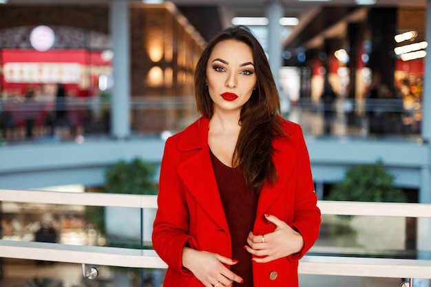 Stylish beautiful girl model looks posing on the background of the shopping center