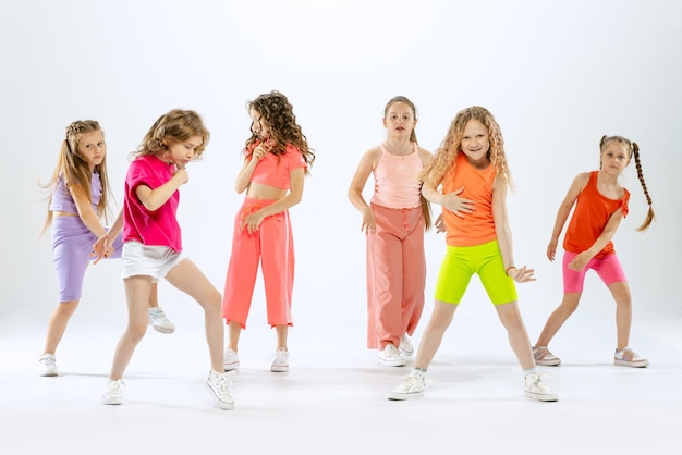 Stylish beautiful girls children dancing training having fun isolated over white studio background