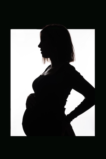 Stylish beautiful pregnant woman in a black dress holds her hands on her stomach