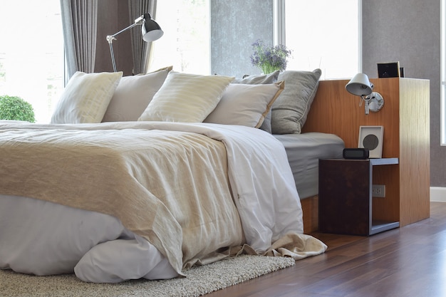 Stylish bedroom interior design with white striped pillows on bed and decorative table lamp.