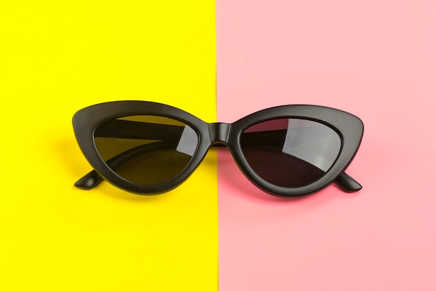 Stylish black sunglasses isolated on trendy pink Flat lay