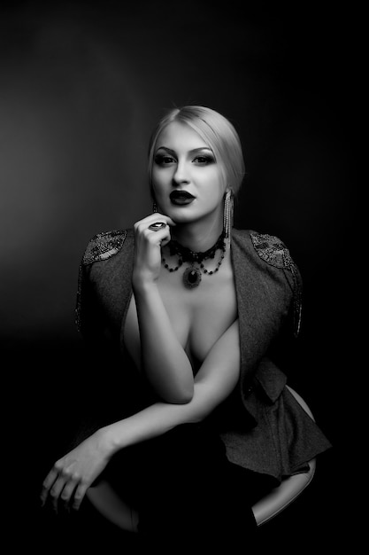 Stylish black and white studio portrait of a lovely woman with bright makeup wears jacket on a naked body