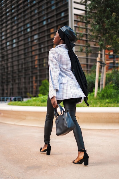 Stylish black woman walking in park in downtown