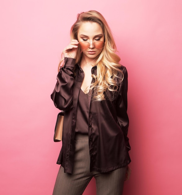 Stylish blond woman in blouse and pants wearing sunglasses