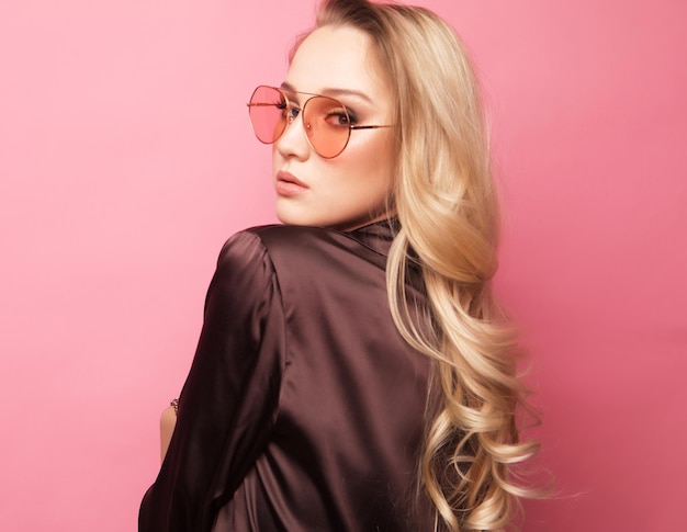 Stylish blond woman in blouse and pants wearing sunglasses