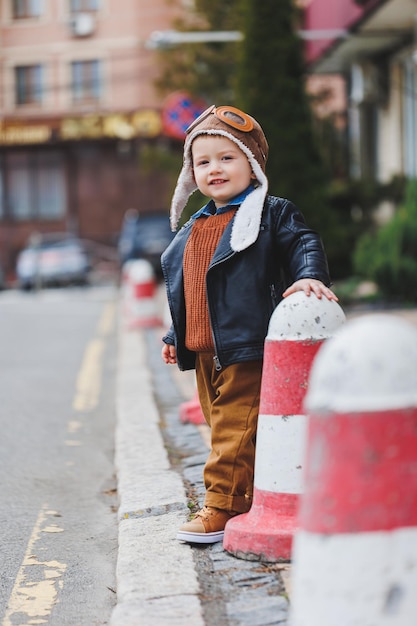 Stylish boy 3 years old in a leather jacket and brown trousers walks on the street Modern child Children's fashion Happy child