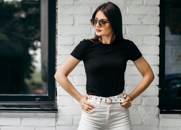 Photo stylish brunette girl wearing black tshirt and glasses posing against street  urban clothing style