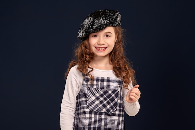 Stylish brunette kid is posing in studio on a black background childrens fashion