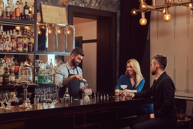 Stylish brutal bartender serves an attractive couple who spend an evening on a date.