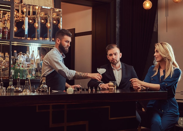 Stylish brutal bartender serves an attractive couple who spend an evening on a date.