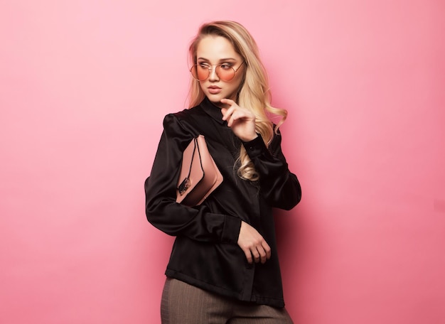 Stylish business woman in blouse and pants posing on pink background