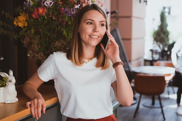 Stylish business woman talking by smartphone at flower shop