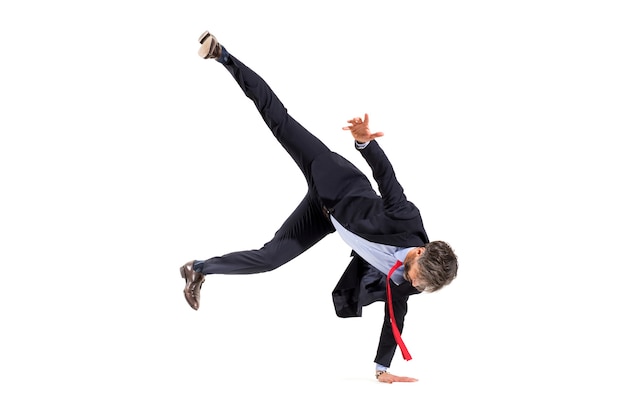 Stylish businessman in a suit doing hip-hop dancing balancing on one hand with legs in the air isolated