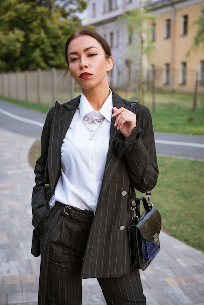 Stylish businesswoman brunette caucasian ethnicity with beautiful makeup posing on the street in a s...