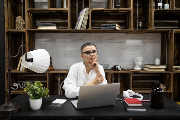 Stylish caucasian european woman in the workplace in glasses behind a laptop