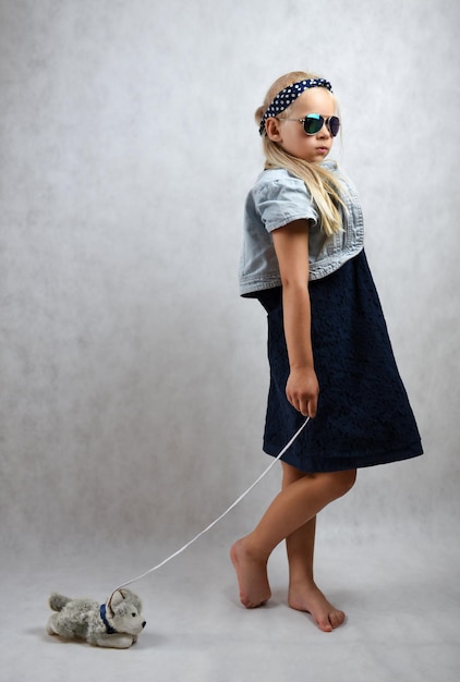 Stylish child with a toy dog isolate fashion